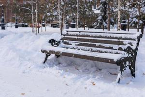 Winterholzbank im schneebedeckten Park - Stadt- und Saisonkonzept foto