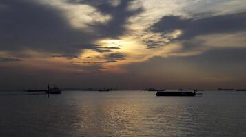 Sonnenuntergang beim das Hafen von industriell Bereich, Silhouette von Lastkahn, schnell Fähre, groß logistisch Schiff. foto