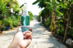 Hand halten ein Flasche von Ethanol oder Ethyl Alkohol sprühen zum basierend Hand reiben ist höchst Wirksam im reduzieren Grippe ein Virus auf Mensch Hände im natürlich Garten. gesund und covid19 Epidemie Konzept. foto