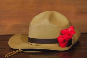 anzac Heer faulenzen Hut mit rot Blume auf Jahrgang Holz Hintergrund . foto