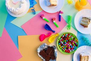 Kuchen, Süssigkeit, Schokolade, Pfeifen, Streamer, Luftballons auf Urlaub Tisch. Konzept von Kinder- Geburtstag Party. Aussicht oben. foto
