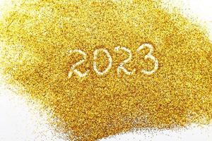 Nummer 2023 auf goldenem Konfetti geschrieben. weihnachts- oder neujahrshintergrund foto