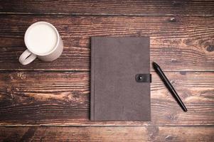 Notizbuch und ein Glas Milch auf dem Schreibtisch foto