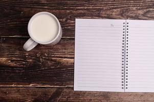 Notizbuch und ein Glas Milch auf dem Schreibtisch foto