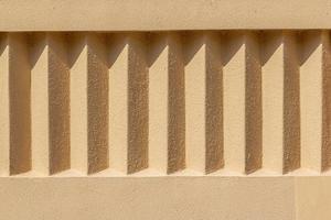 Beige Außen Stuck Mauer mit wiederholen Einzelheiten. Rau Oberfläche im das Sonne mit Schatten. Rau Textur und Hintergrund foto