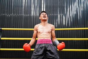 muay thailändisch, das kriegerisch Kunst von Thailand, Boxer Glück wann er Gewinnt durch Stehen auf das Boxen Ring und schreien zufriedenstellend foto