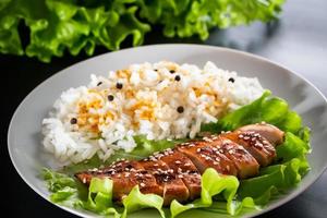 hausgemachtes Essen - Teriyaki-Huhn mit weißem Reis und Pfeffer auf einem schwarzen Hintergrund foto