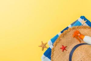 Beach Flat Lay Zubehör mit Kopierraum. gestreiftes blau-weißes Handtuch, Muscheln, Staw-Sonnenhut und eine Flasche Sonnencreme auf gelbem Hintergrund. sommerferienkonzept foto