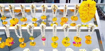 viele Girlande Blume hängend auf Weiß rostfrei Stahl Aufhänger zum Anbetung das Buddha beim thailändisch Tempel. Religion, Kultur und Respekt oder Vertrauen Konzept foto