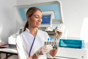 Labor Assistent Putten Prüfung Röhren in das Halter. Wissenschaftler Arzt suchen beim Blut Prüfung Tube Arbeiten beim Biochemie Experiment im Mikrobiologie Krankenhaus Labor. foto