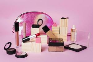 Make-up-Produkte und glänzende Kosmetiktasche auf rosa Hintergrund