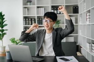 asiatisch Geschäft Mann sind Erfreut und glücklich mit das Arbeit Sie tun auf ihr Tablette, Laptop und nehmen Anmerkungen beim das Büro. foto