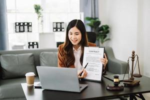 asiatisch weiblich Anwalt chatten online mit Klient auf Laptop, Smartphone diskutieren Einzelheiten von Klage. im modern Büro foto