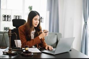 asiatisch weiblich Anwalt chatten online mit Klient auf Laptop, Smartphone diskutieren Einzelheiten von Klage. im modern Büro foto