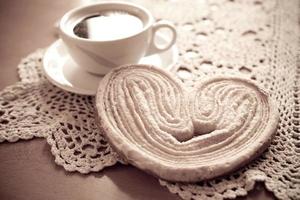 Weiß Tasse von schwarz Kaffee und ein Süss butterartig Plätzchen auf das Tabelle foto