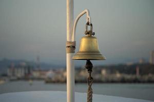 Kupferglocke auf der Yacht auf dem Hintergrund der erodierten Küste foto