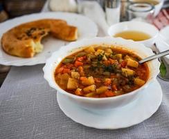 Lagman in einem weißen Teller gegen eine weiße Tischdecke, Tatar Küche foto