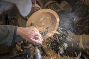 Herstellung einer Holzschale auf einer Drehmaschine in einer alten kleinen Werkstatt foto