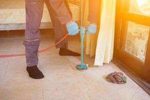 vernichten Termite Steuerung Unternehmen Mitarbeiter ist mit ein Termite Sprühgerät beim Kunden Haus und suchen zum Termite Nester zu beseitigen. vernichten Steuerung Arbeiter Sprühen chemisch Insekt abstoßend foto