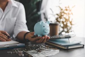 Geschäftsfrau Hand halten Blau Schweinchen Bank auf Holz Tabelle Hintergrund, Speichern Geld Reichtum und finanziell Konzept, Finanzen, Investition, finanziell Planung. finanziell Planung Anzahlung zum Ruhestand. foto