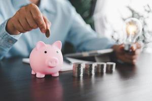 Geschäftsfrau Hand halten die Glühbirne und Putten Münze im Schweinchen Bank. Idee von Speichern Energie und Buchhaltung Finanzen im Zuhause und Familie, speichern Welt und Energie Leistung. speichern Energie planen Konzept foto