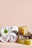 Spa einstellen mit gerollt Weiß Handtuch, Kamille Blume und Stapel von organisch natürlich Seife Riegel mit natürlich Kräuter- Zutaten foto