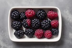 Brombeeren und Himbeeren im ein Teller auf ein Weiß Hintergrund. generativ ai foto