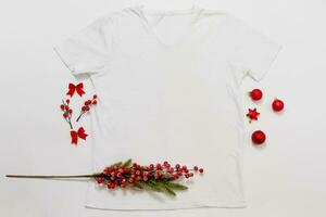 schließen sie herauf weißes leeres schablonen-t-shirt mit kopienraum und weihnachtsfeiertagskonzept. Draufsichtmodellt-shirt und rote Feiertagsdekorationen auf weißem Hintergrund. frohes neues jahr zubehör. Weihnachts-Outfit foto