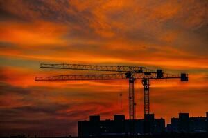 natürlich dramatisch mit Wolken bunt städtisch Sonnenuntergang mit Konstruktion Kran foto