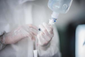 Medizin Gesundheit Krankheit Behandlung Konzept, Arzt injiziert flüssige Droge in Kochsalzlösung Beutel im Krankenzimmer, Tropfbehandlung intravenöse Infusion, Klinik Gesundheitswesen medizinisches Konzept foto