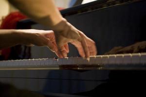 Nahansicht auf das Hände von ein Frau spielen das Klavier mit Musik- Schlüssel foto