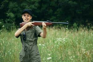 Frau halten ein Waffe Grün Overall schwarz Deckel Grimasse foto