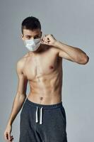 Mann mit muskulös Torso schwarz kurze Hose medizinisch Maske Schutz foto