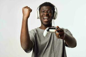 ein Mann von afrikanisch Aussehen im Kopfhörer mit ein Gamepad im seine Hände Theaterstücke Video Spiele Technologie foto