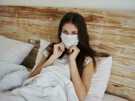 jung Frau im ein medizinisch Maske Lügen im Bett oben Aussicht foto