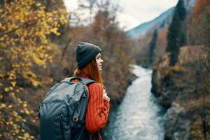 Frau Wanderer mit ein Rucksack auf ihr zurück in der Nähe von ein Berg Fluss im Natur, zurück Aussicht foto