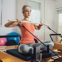 blond Frau ist ausüben auf Pilates Reformer Bett im ihr heim. foto