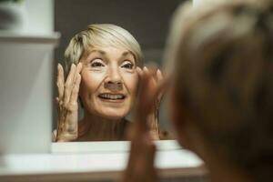 schön reifen Frau ist massieren ihr Gesicht im das Badezimmer. foto
