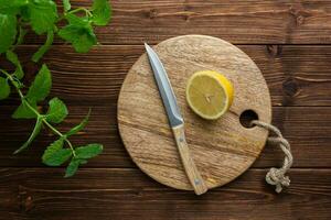 Zitrone mit Messer auf Schneiden Tafel auf hölzern Hintergrund. foto