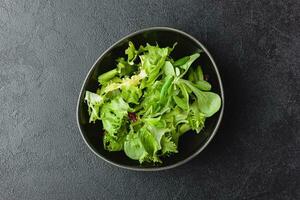 grüne salatblätter in schüssel auf schwarzem tisch. foto