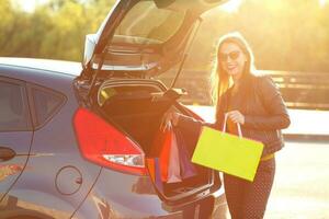 kaukasisch Frau Putten ihr Einkaufen Taschen in das Auto Kofferraum foto