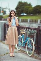 junge schöne, elegant gekleidete Frau mit Fahrrad foto