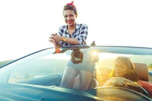 zwei jung glücklich Mädchen Fahren ein Cabriolet foto