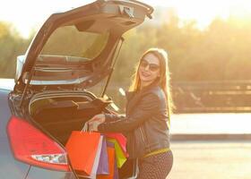 Frau Putten ihr Einkaufen Taschen in das Auto Kofferraum foto