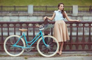 junge schöne, elegant gekleidete Frau mit Fahrrad foto