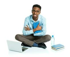 glücklich afrikanisch amerikanisch Hochschule Schüler mit Laptop, Bücher und Flasche von Wasser Sitzung auf Weiß foto