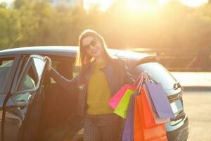 lächelnd kaukasisch Frau Putten ihr Einkaufen Taschen in das Auto foto