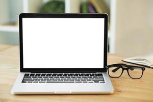 Laptop mit leerem weißen Bildschirm mit Brille auf Holzschreibtisch foto