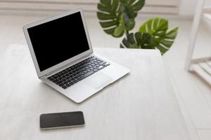 minimalistischer Büro-Hochsicht-Laptop mit Monstera-Pflanze foto