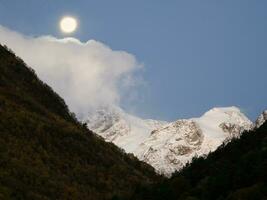 verschwommen Mond mit Natur Hintergrund. voll Mond Über das Berg. voll Mond Über das schneebedeckt Steigung von das kaukasisch Berge. foto